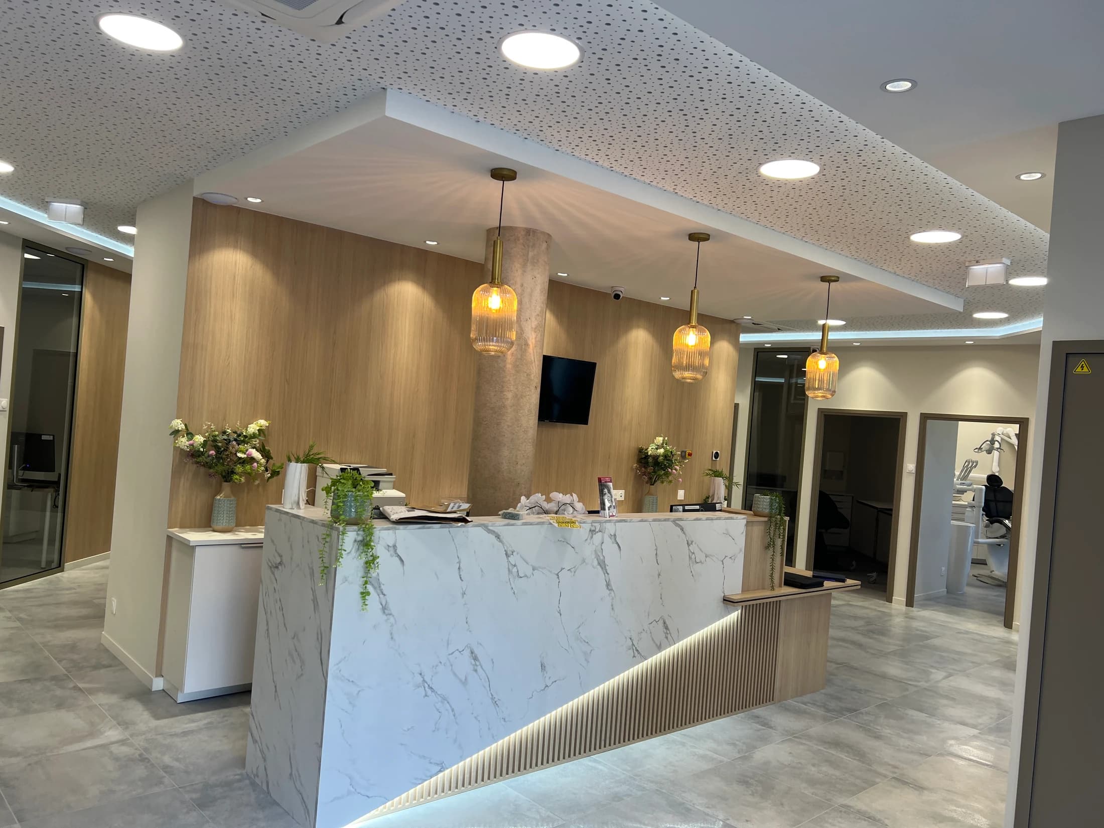 Banque d’accueil à parement effet marbre avec suspensions dorées et bois cannelé
