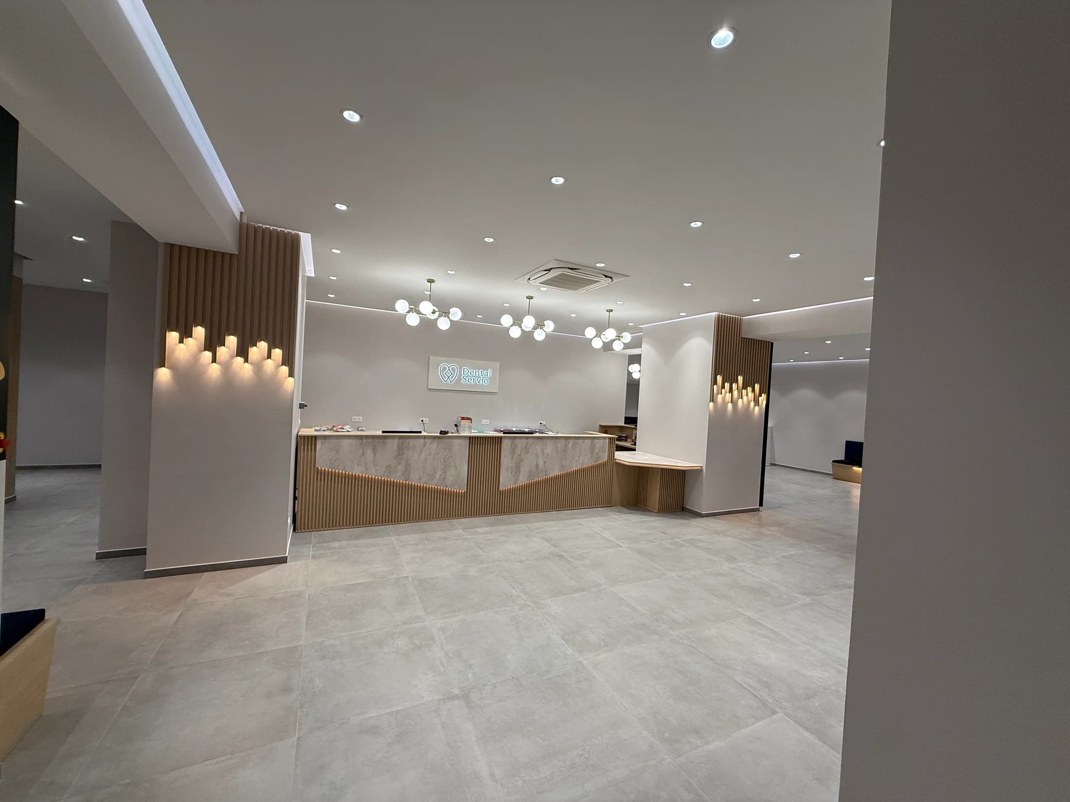 Vue d’ensemble de la réception Dental Servio avec son comptoir et ses appliques lumineuses