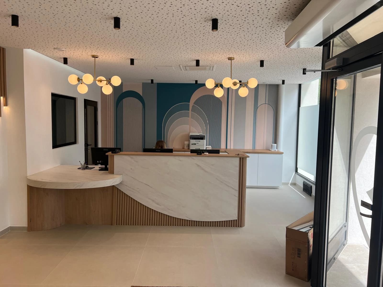 Réception arrondie avec comptoir à deux hauteurs et décor mural aux motifs d’arches