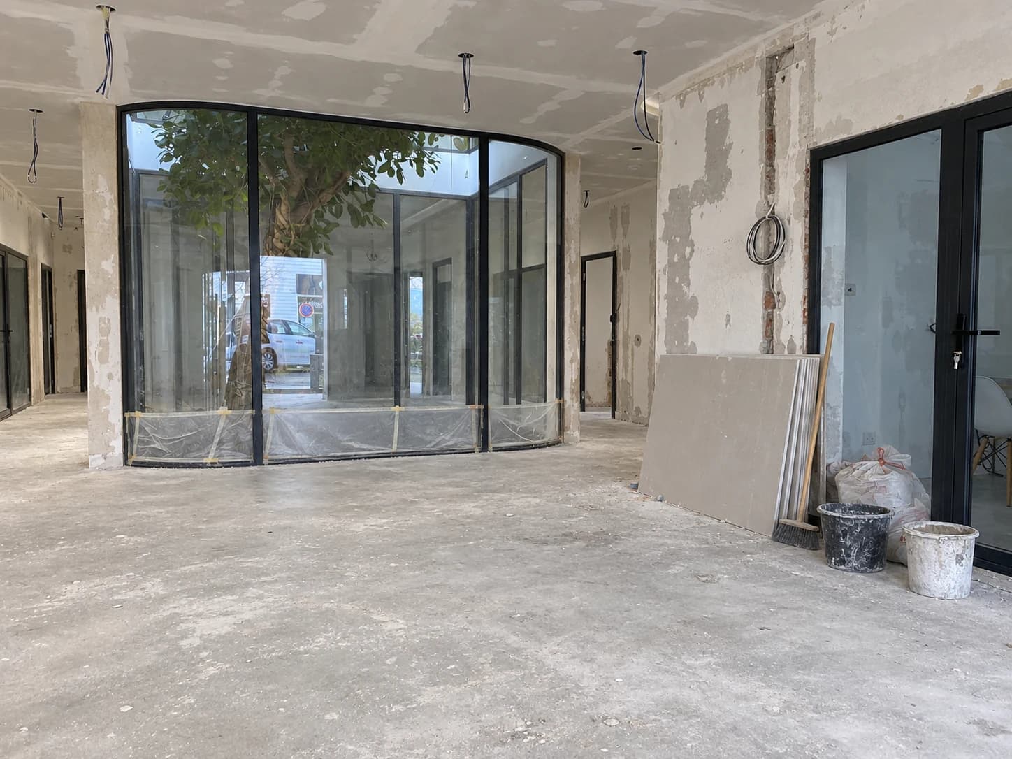 Simulation IA d’un début de chantier autour du patio vitré : sol brut et espace sans comptoir